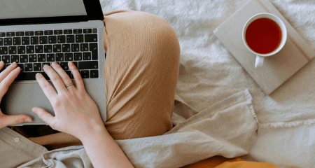 woman sitting on bed with laptop